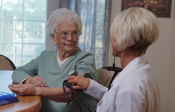 nurse checking senior woman's blood pressure